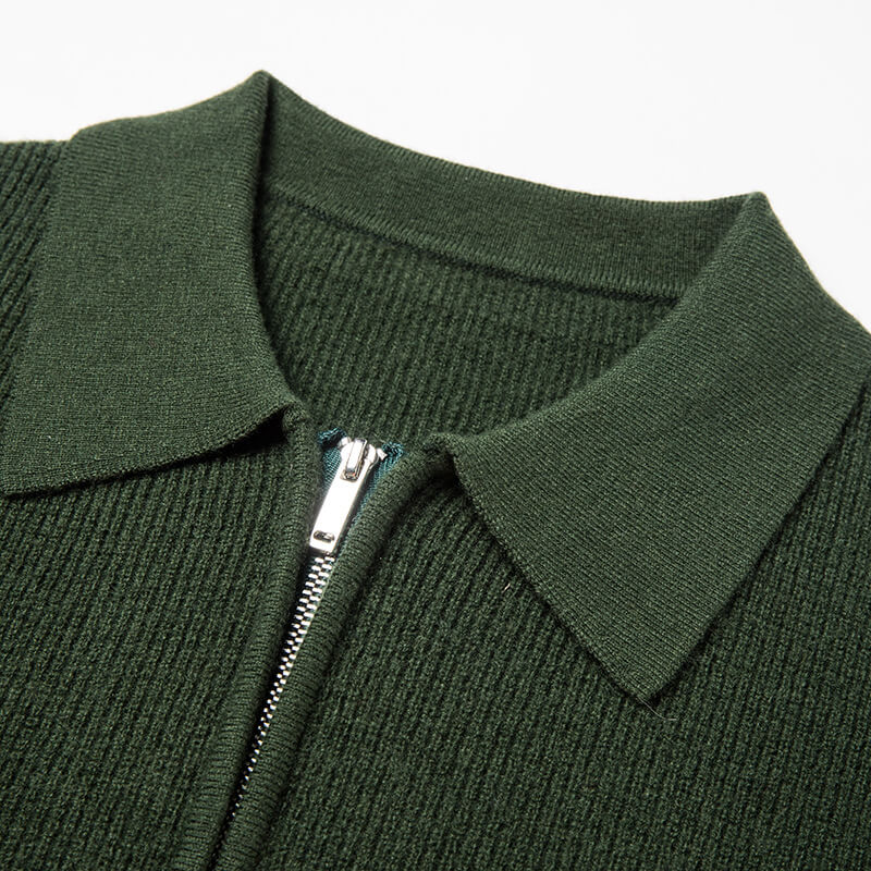 Close-up of a forest green quarter-zip knit polo sweater highlighting the ribbed collar, zipper, and fine knit texture.