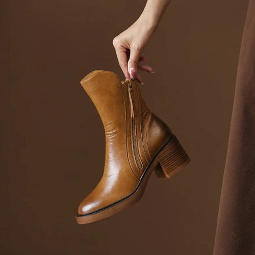 Tan grained ankle boot with a full-length side zip, round toe, and a sturdy stacked block heel against a brown background.