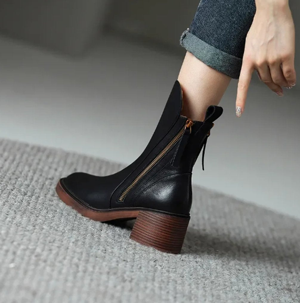 Black grained leather ankle boot featuring a full-length side zip, stacked block heel, and knotted back tie detail.