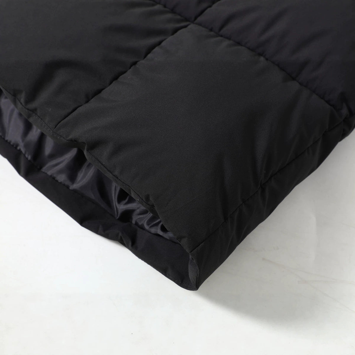 Close-up of the black Chevron-Quilted Longline Puffer Coat showing the chevron-quilted fabric and padded construction.