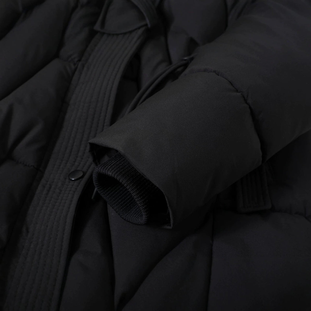 Close-up of the black Chevron-Quilted Longline Puffer Coat sleeve, highlighting the padded construction, quilted texture, and cuff detail.