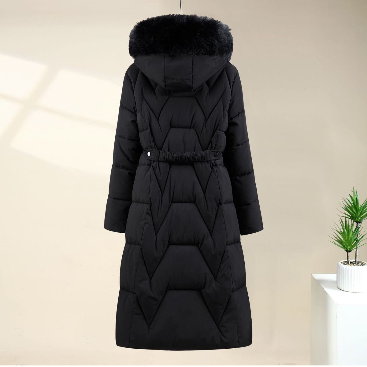 Black Chevron-Quilted Longline Puffer Coat shown from the front, featuring a plush-trimmed hood, chevron quilting, drawstring waist, and longline fit.