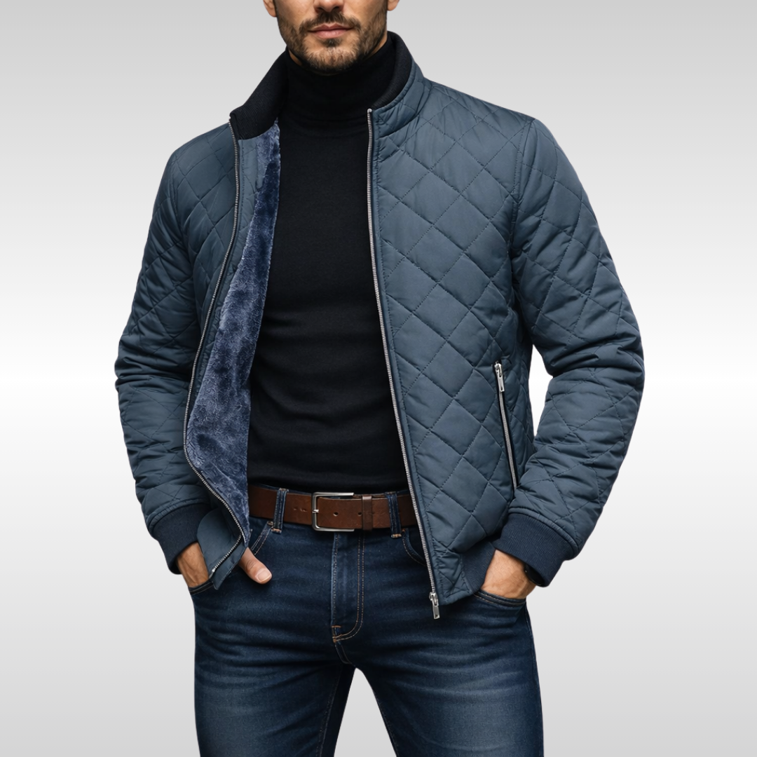 Man wearing a blue diamond-quilted zip-up jacket with a stand collar, warm fleece lining, and black turtleneck sweater.