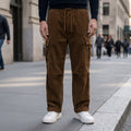 Brown corduroy cargo pants with flap pockets, drawstring waist, and a relaxed straight-leg fit worn with white sneakers.