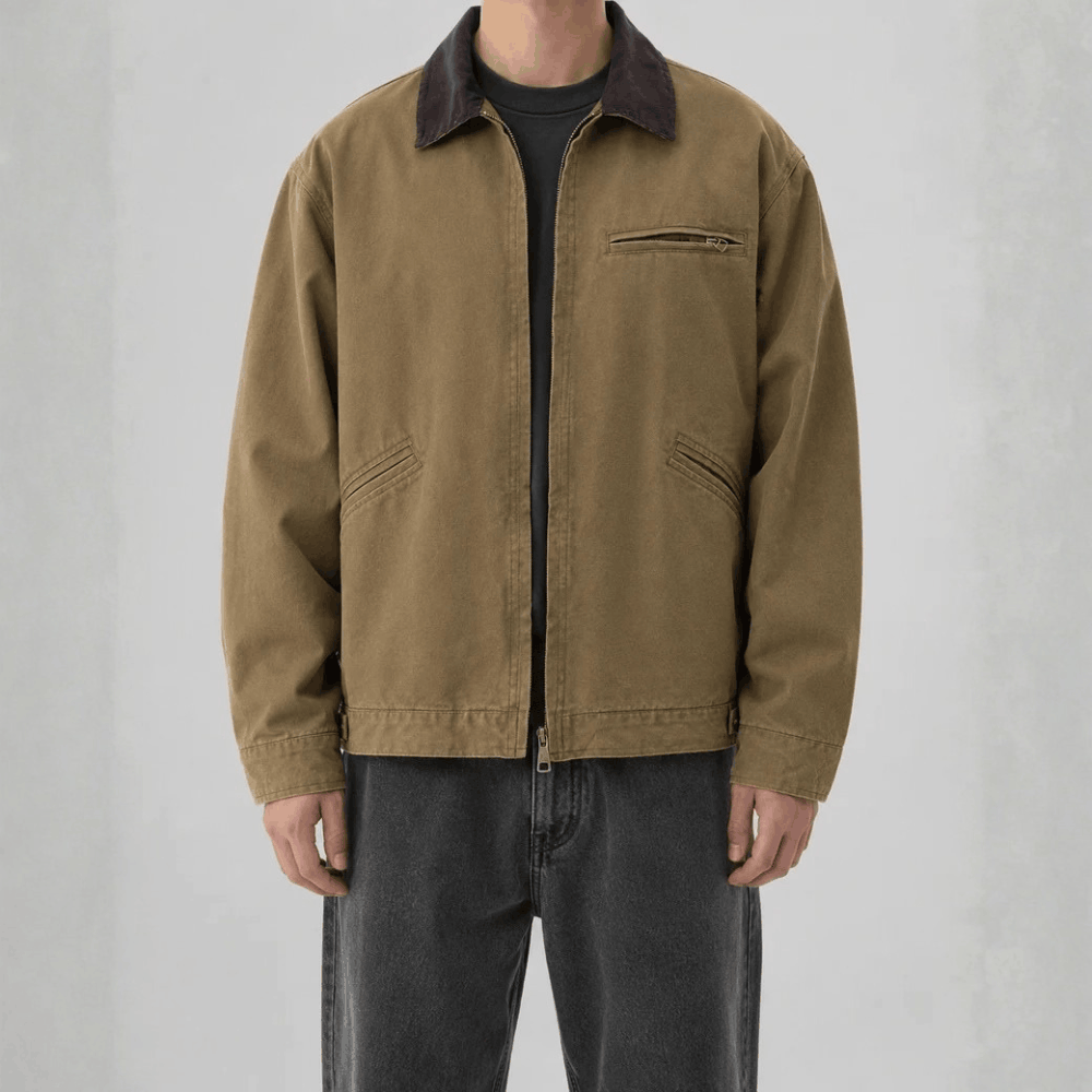 Front view of a model wearing a brown khaki cotton canvas barn jacket featuring a dark brown corduroy collar and zip chest pocket.