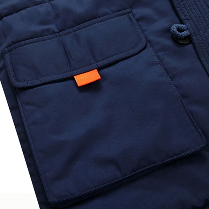 Navy blue cotton-padded parka featuring a large flap pocket with a vibrant orange tab and a sturdy button closure.