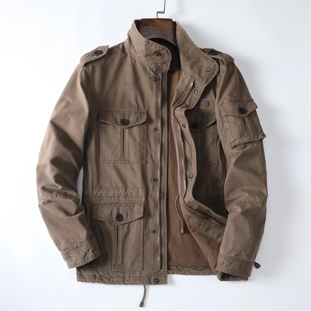Front product view of the open brown cotton utility cargo jacket on a hanger displaying shoulder epaulets, stand collar, front zipper with snap closure, and multiple flap pockets.