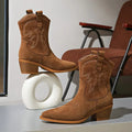 Close-up of brown cowboy ankle booties showing the embroidered shaft and pointed toes