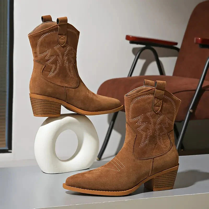 Close-up of brown cowboy ankle booties showing the embroidered shaft and pointed toes
