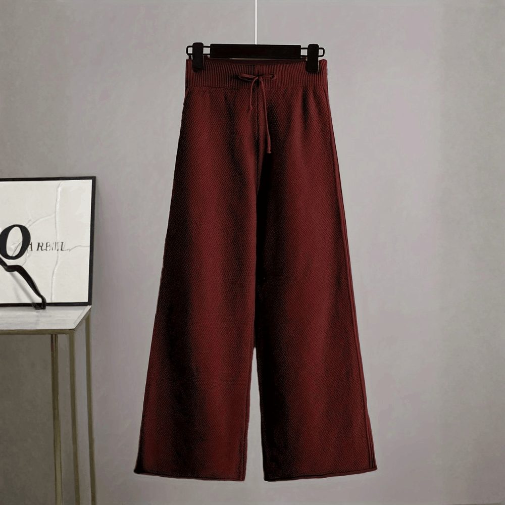 Front view of the high-waisted deep burgundy wine wide-leg knit trousers on a hanger showing the drawstring detail.