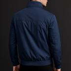 Navy blue weather-resistant bomber jacket with a structured fit and clean back yoke detail on a dark background.
