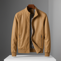 Tan weather-resistant bomber jacket with a stand collar, zippered pockets, and a black-and-white gingham-check lining.