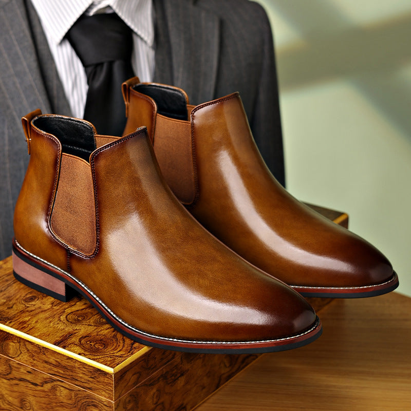 Burnished tan leather Chelsea boots with a pointed toe, elastic side panels, stitched welt, and a low stacked heel.