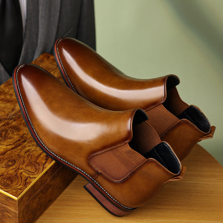 Burnished tan leather Chelsea boots with a pointed toe, elastic side panels, and a stitched welt stacked heel.