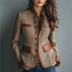 Tailored tan tweed blazer featuring brown faux leather trim, a structured button-front, and flap pockets.