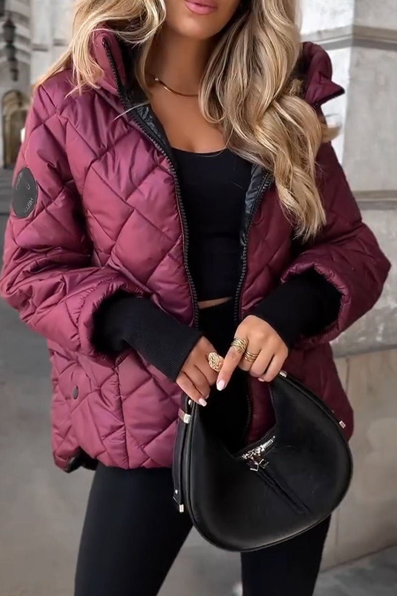 Burgundy diamond-quilted puffer jacket with a stand collar, hooded back, and relaxed fit worn over a black top.