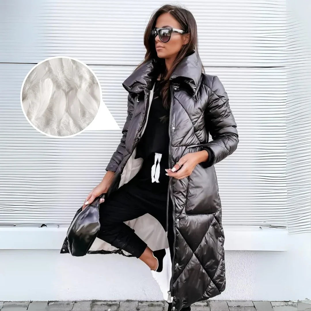 High-shine black longline puffer coat with diamond quilting, funnel collar, and zip-snap closure worn over joggers and sneakers.