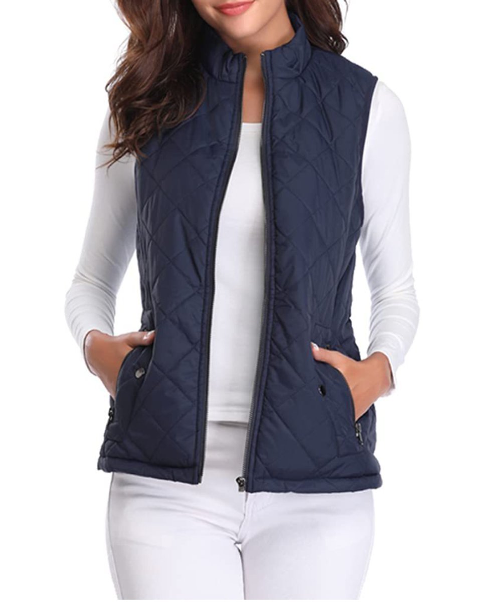 Front view of a model wearing the diamond-quilted zip-up vest with stand collar in deep navy blue over a white top.