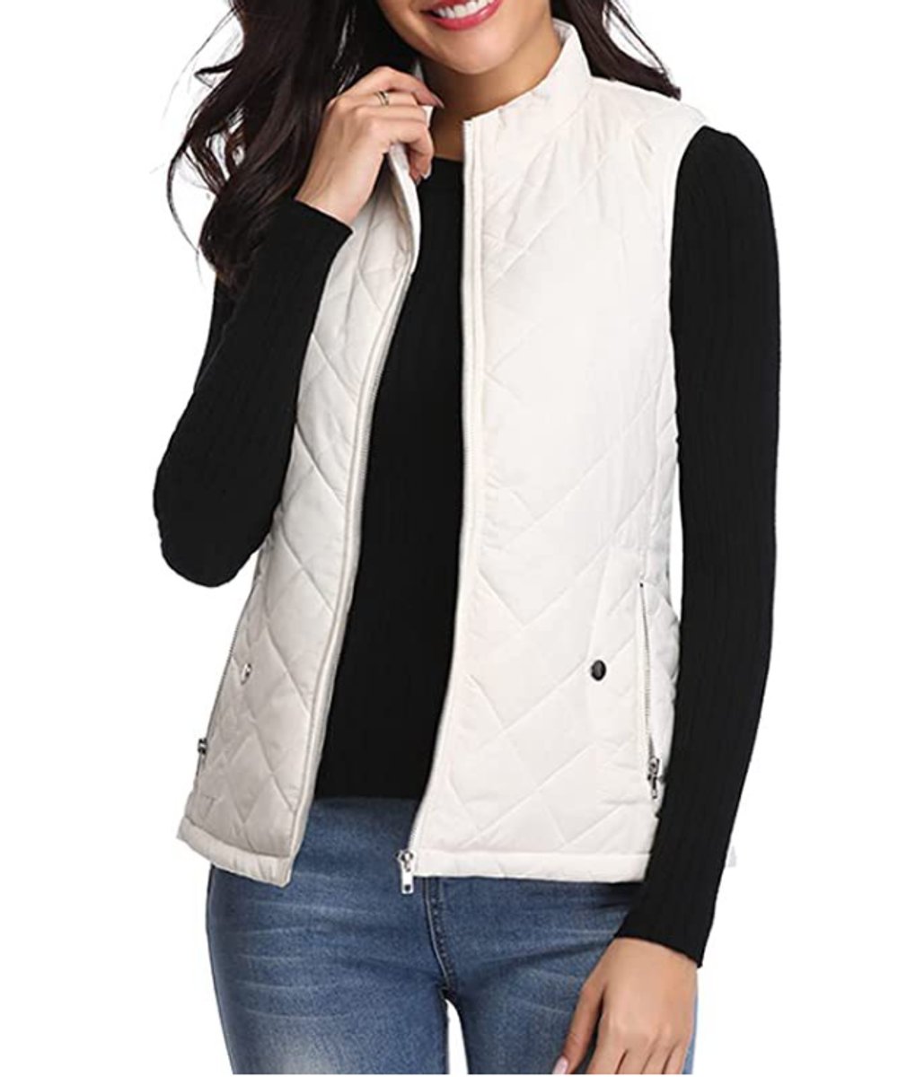Front view of a model wearing the diamond-quilted zip-up vest with stand collar in white cream layered over a black long-sleeve top.