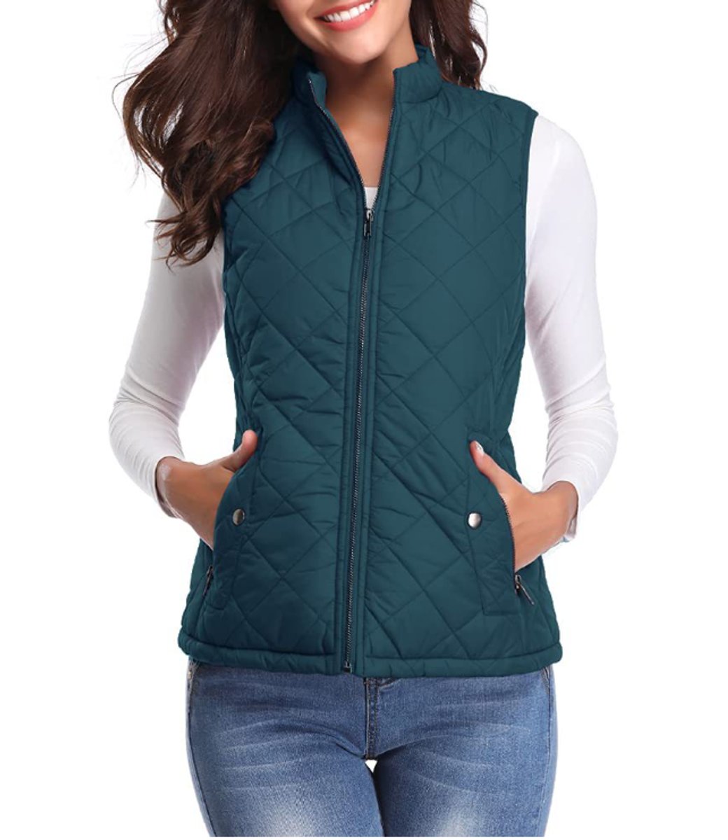 Front view of a model wearing the diamond-quilted zip-up vest with stand collar in deep teal green paired with blue jeans.