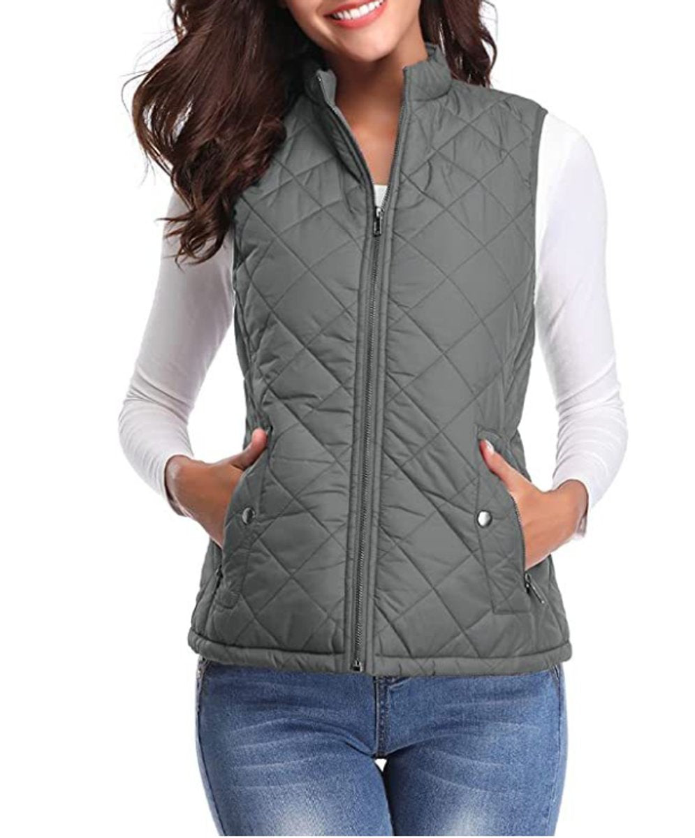 Front view of a model wearing the diamond-quilted zip-up vest with stand collar in charcoal gray over a white top and blue jeans.