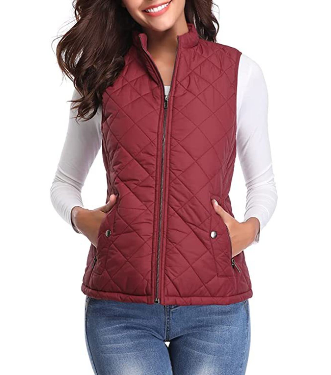 Front view of a model wearing the diamond-quilted zip-up vest with stand collar in burgundy paired with blue denim jeans.