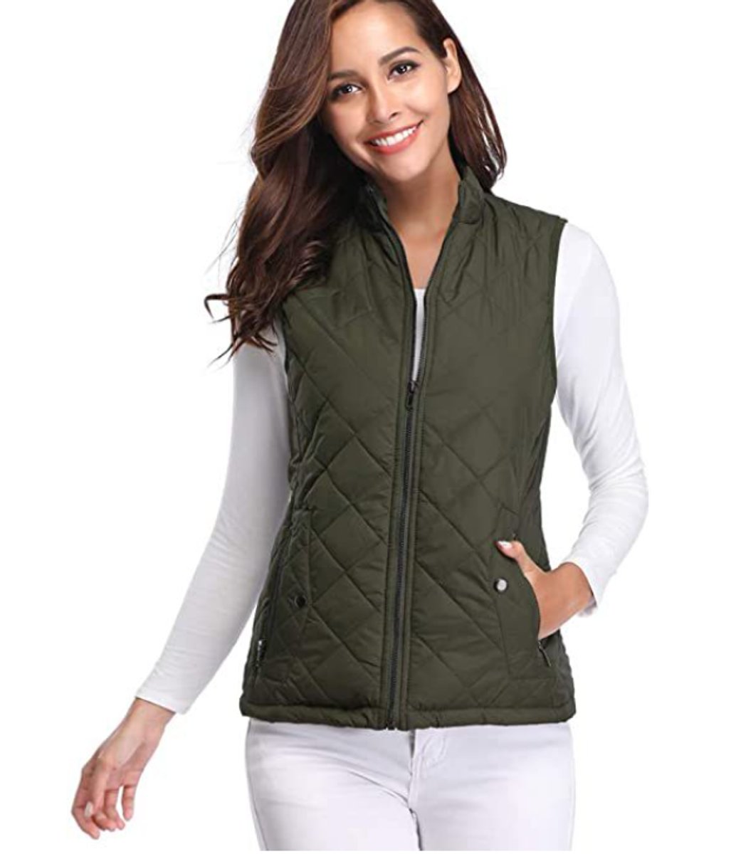 Front view of a model wearing the diamond-quilted zip-up vest with stand collar in olive green over a white long-sleeve top.