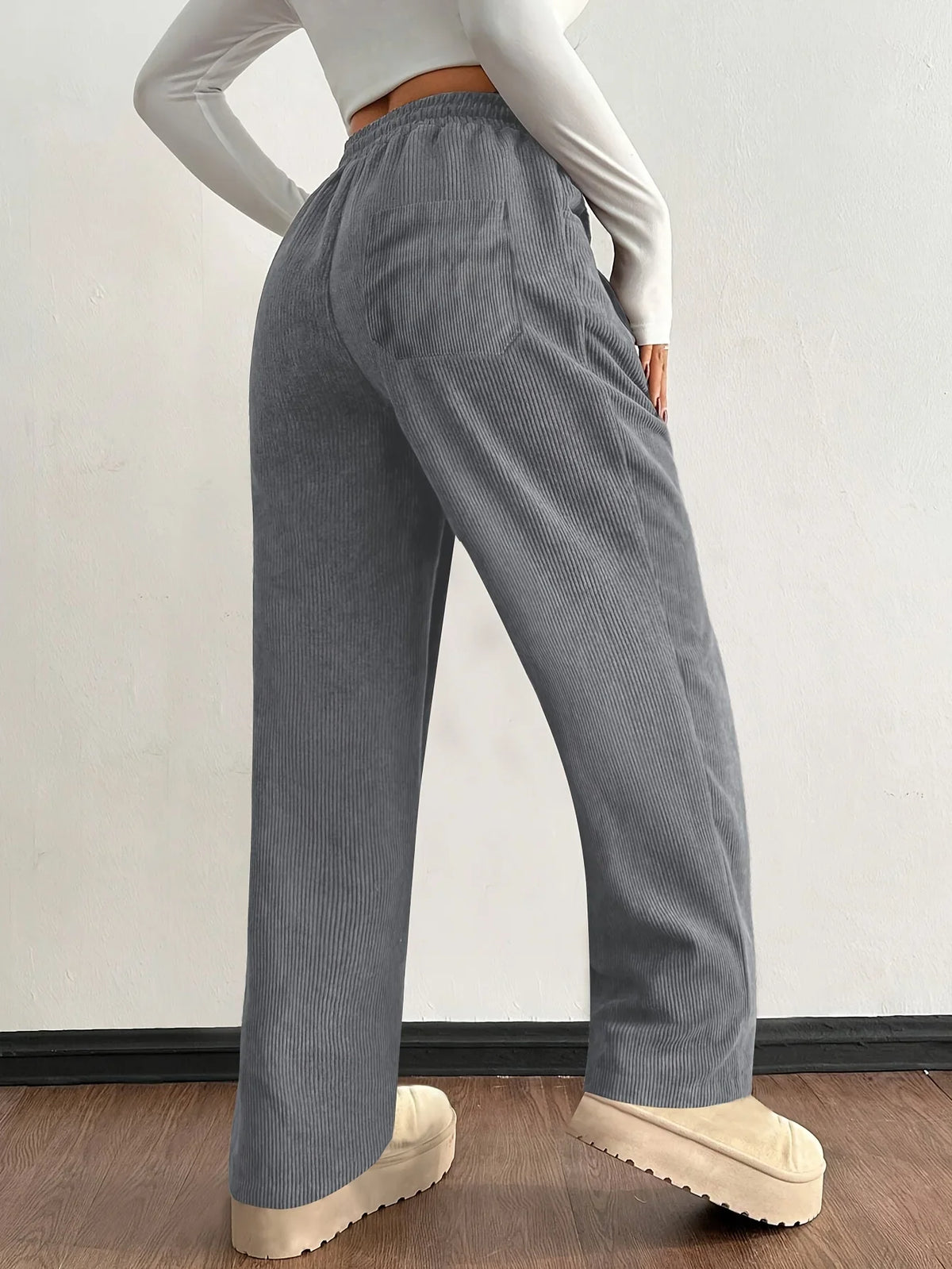 Gray corduroy pants shown from the side with wide-leg fit