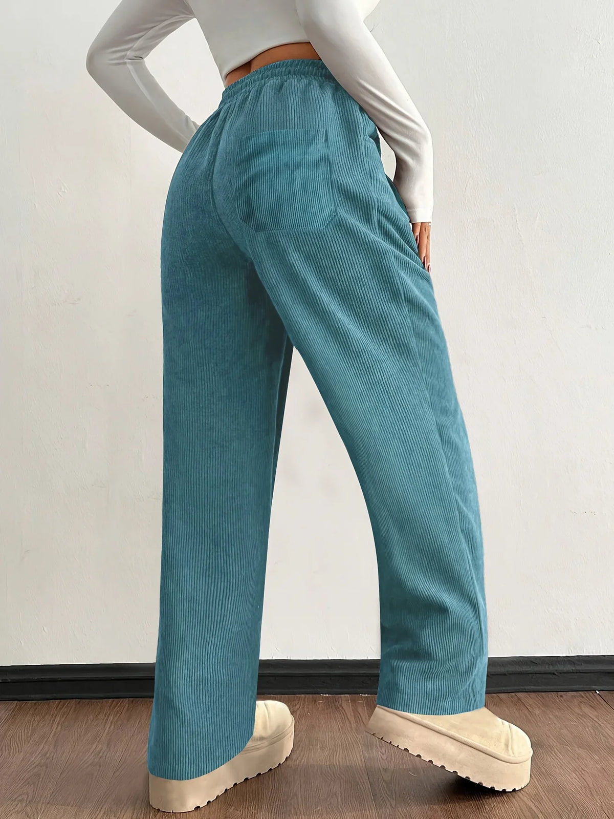 Teal corduroy pants shown in a side view with wide-leg fit and drawstring waist