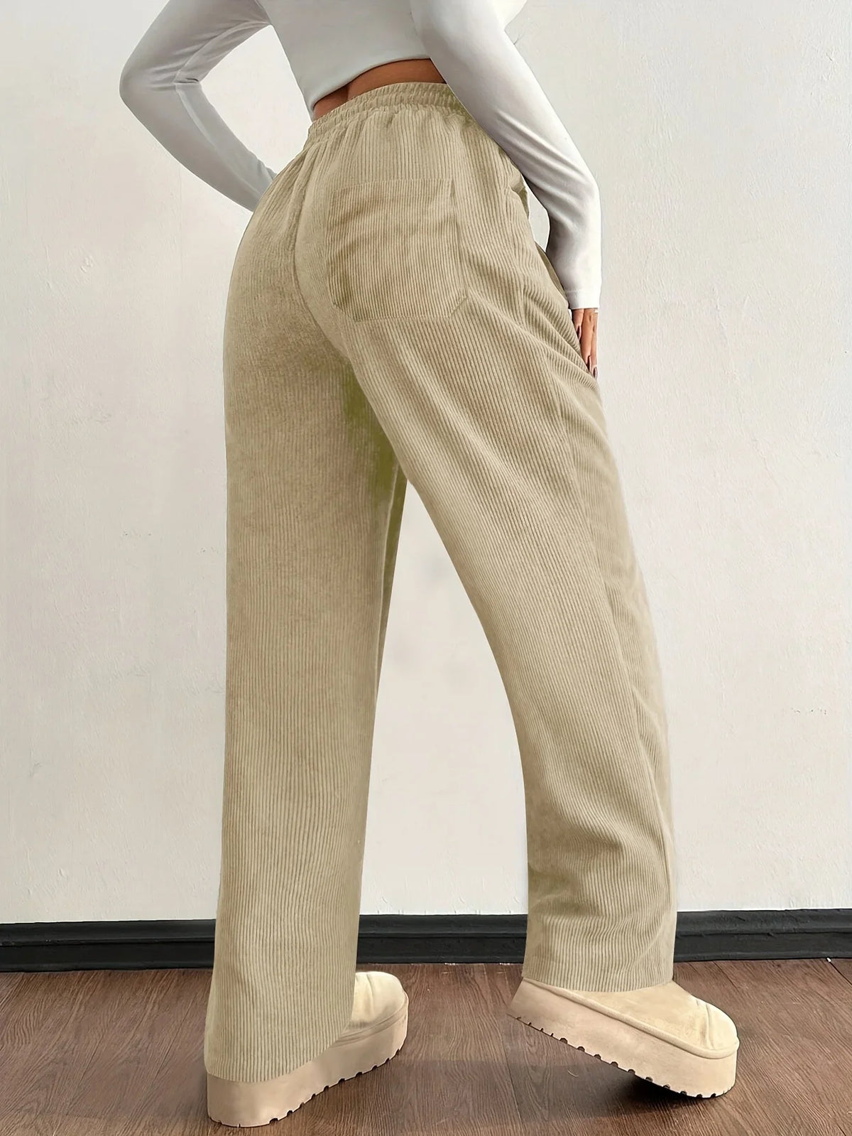 Beige corduroy pants shown from the side with wide-leg fit
