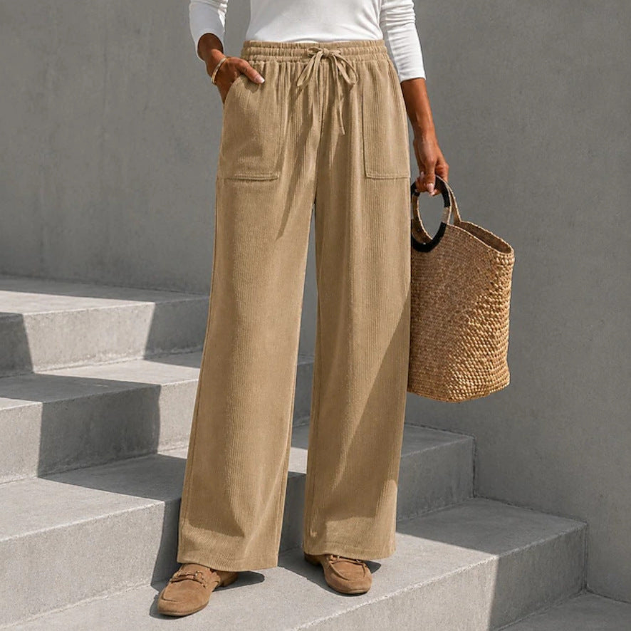 Beige an elastic drawstring waist and front patch pockets, styled with loafers on concrete steps.