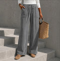 Gray wide-leg corduroy pants featuring an elastic drawstring waist and front patch pockets, styled with loafers.