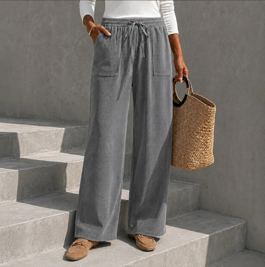 Gray wide-leg corduroy pants featuring an elastic drawstring waist and front patch pockets, styled with loafers.