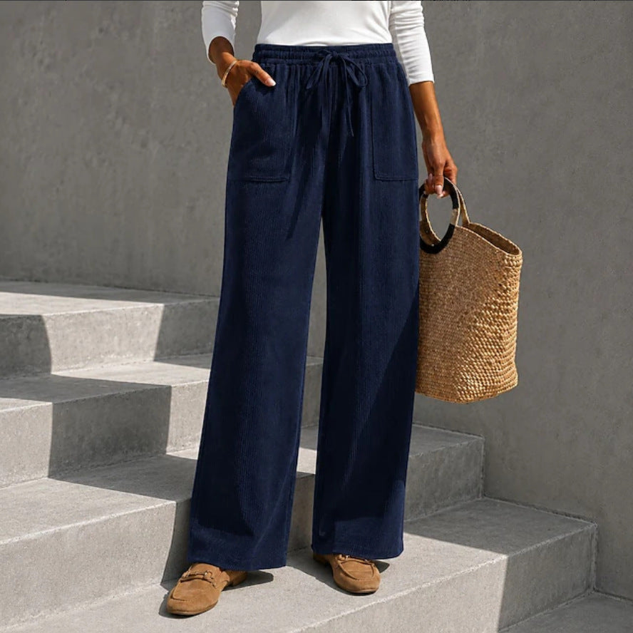 Navy blue wide-leg corduroy pants with an elastic drawstring waist and front patch pockets, styled with loafers.