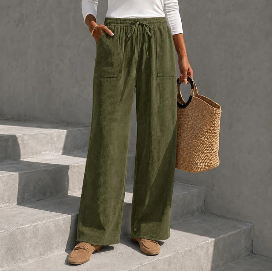 Olive green wide-leg corduroy pants featuring an elastic drawstring waist and front patch pockets on concrete stairs.