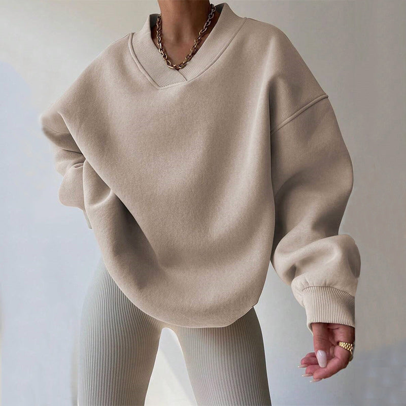 Beige oversized V-neck sweatshirt featuring dropped shoulders, ribbed cuffs, and a relaxed fit, paired with light knit pants.