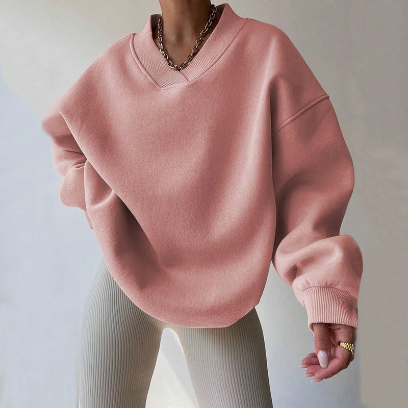 Light pink oversized V-neck sweatshirt with dropped shoulders, ribbed cuffs, and a relaxed fit, paired with light knit pants.
