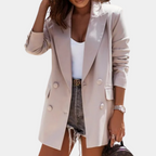Beige double-breasted mid-length blazer in smooth tailored fabric with structured lapels and button detailing.