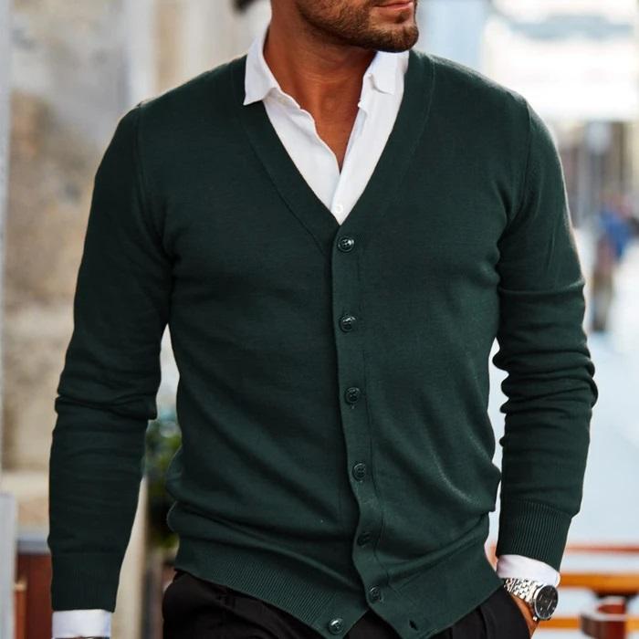 Dark green fine-gauge V-neck cardigan with a button front, ribbed cuffs, and hem layered over a white collared shirt.