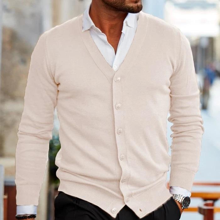 Beige fine-gauge V-neck cardigan in a smooth knit, worn buttoned over a crisp white collared shirt with ribbed cuffs.