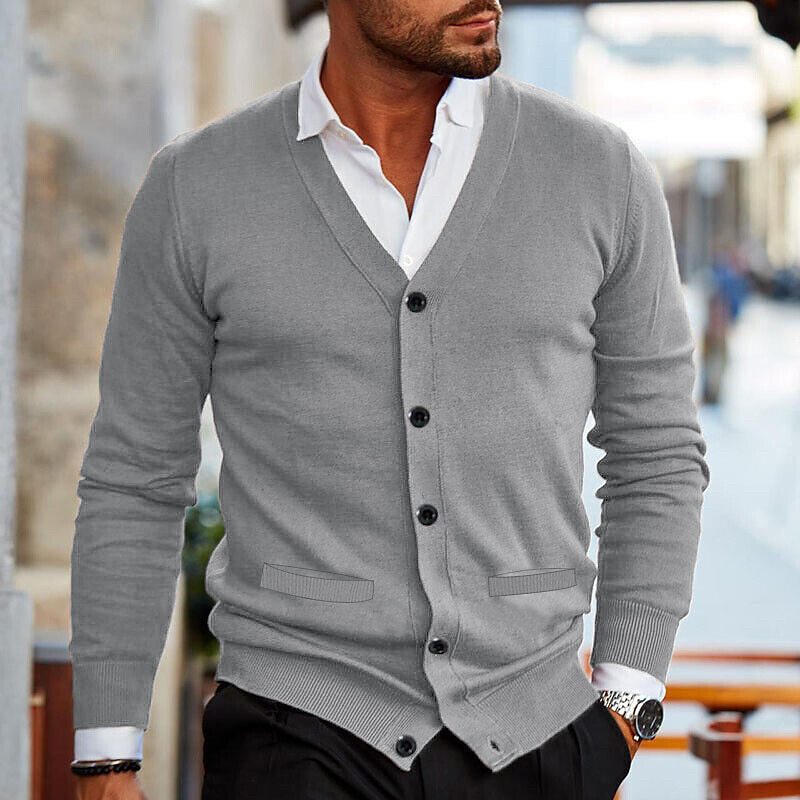 Gray fine-gauge V-neck cardigan with a button front, layered over a crisp white collared shirt and dark trousers.