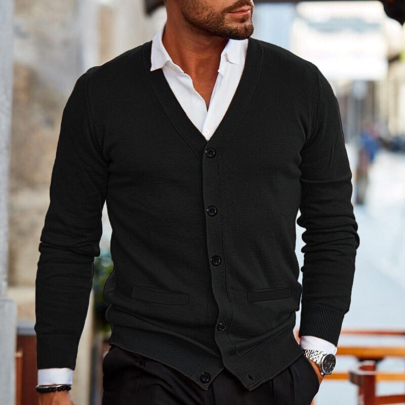 Black fine-gauge V-neck cardigan with a button front, ribbed cuffs, and hem, layered over a crisp white collared shirt.