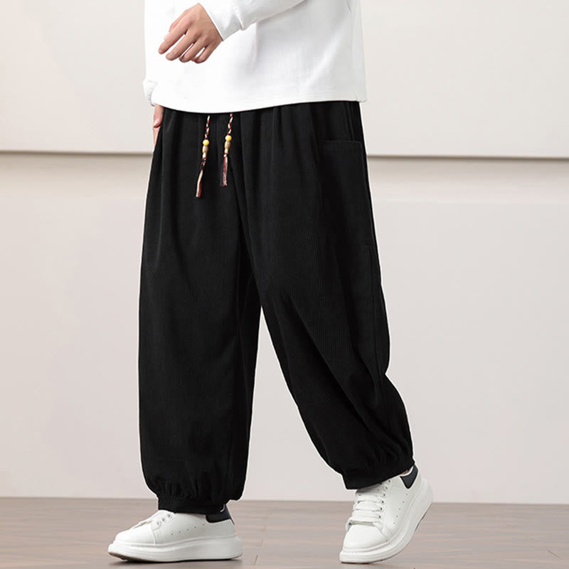Black fine-wale corduroy harem pants with side patch pockets, beaded drawstring waist, and cuffed ankles.
