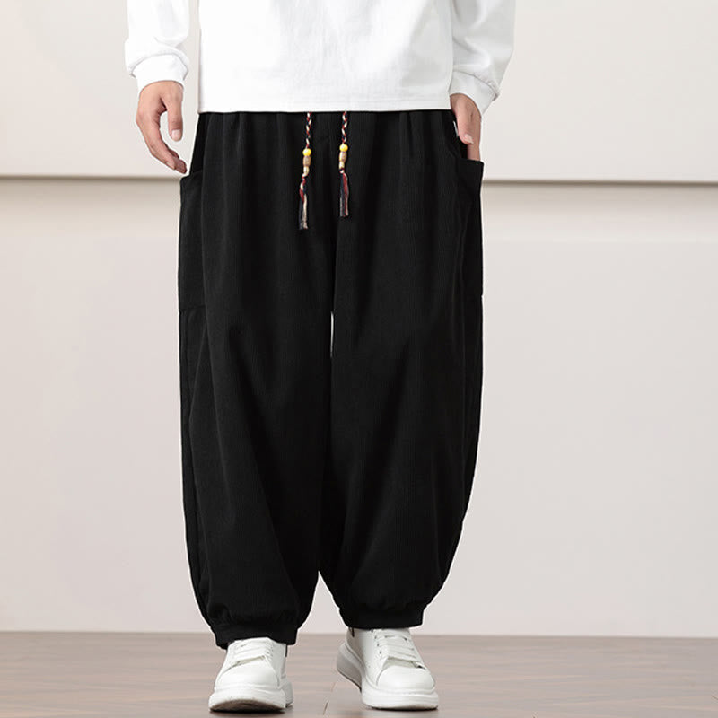 Black fine-wale corduroy harem pants with side patch pockets, beaded drawstring waist, and cuffed ankles.