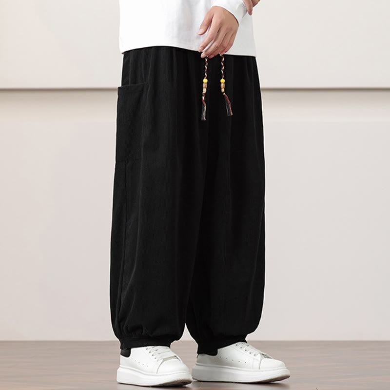 Black fine-wale corduroy harem pants featuring side patch pockets, a beaded drawstring waist, and cuffed ankles.