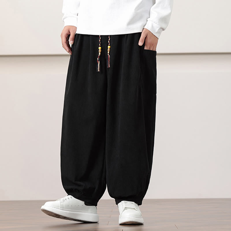 Black fine-wale corduroy harem pants with side patch pockets, beaded drawstring waist, and cuffed ankles.