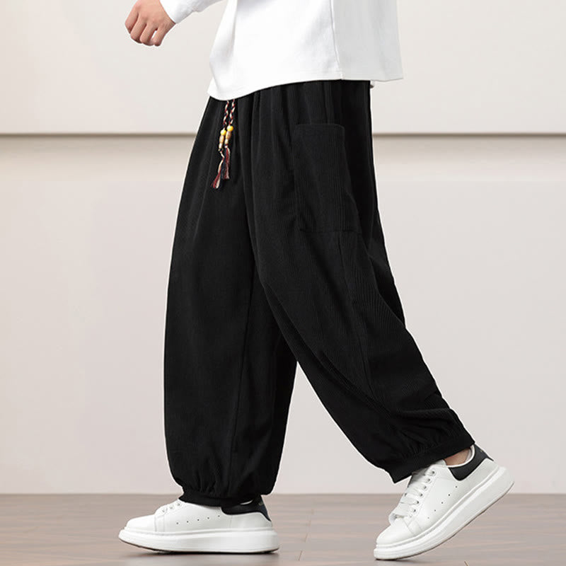 Black fine-wale corduroy harem pants featuring side patch pockets, a beaded drawstring waist, and cuffed ankles.
