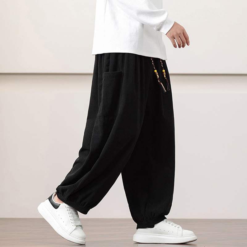 Black fine-wale corduroy harem pants with side patch pockets, beaded drawstring waist, and cuffed ankles worn with sneakers.