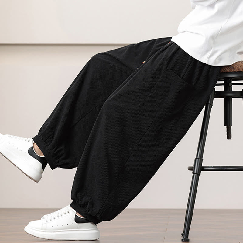 Black fine-wale corduroy harem pants featuring side patch pockets, a beaded drawstring waist, and cuffed ankles.