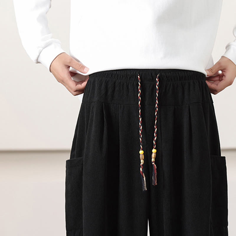 Black fine-wale corduroy harem pants with a beaded drawstring waist and deep side patch pockets.